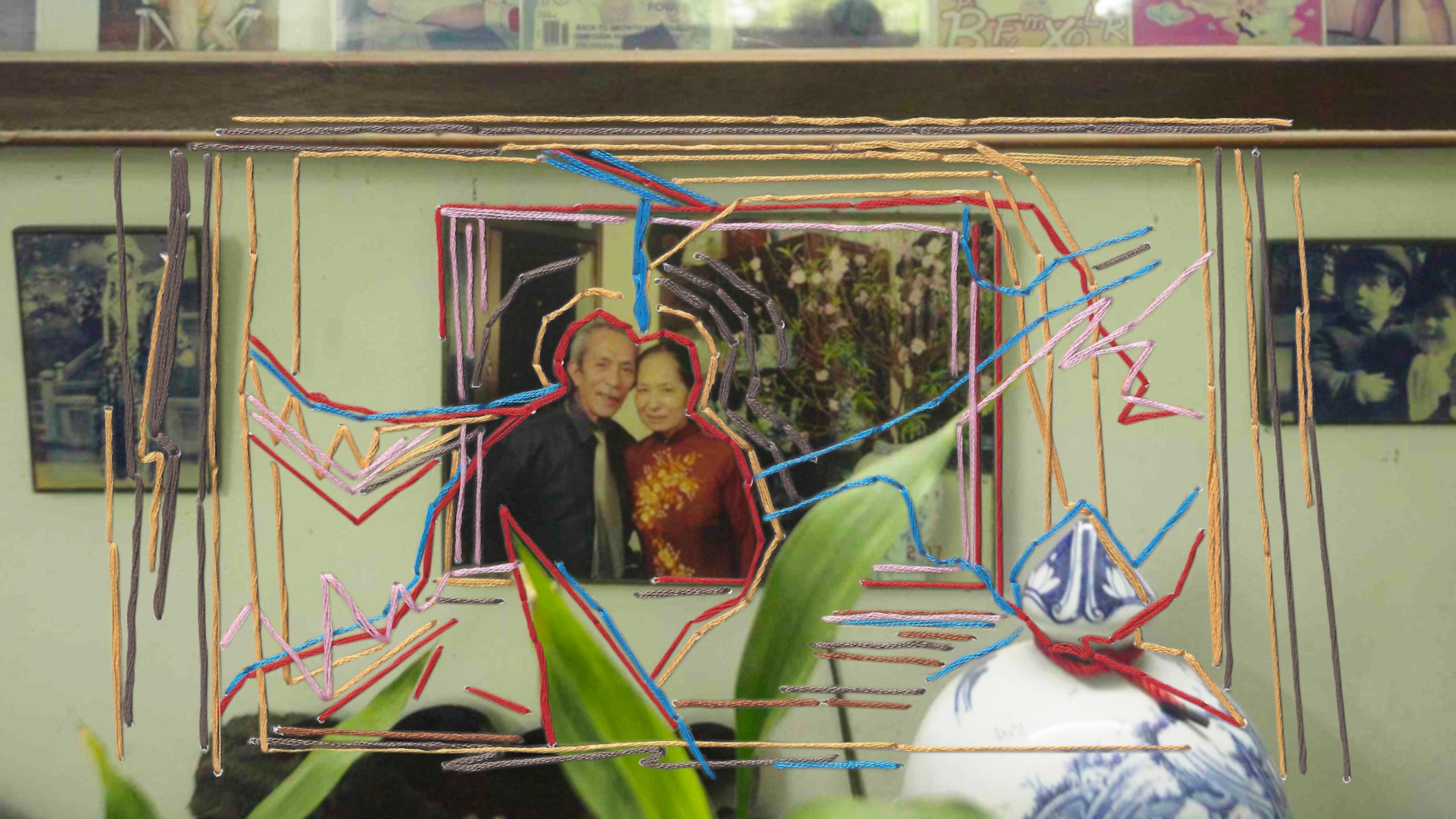 Photo of a framed picture with colourful string art overlays, featuring plants in the foreground and other photos around.