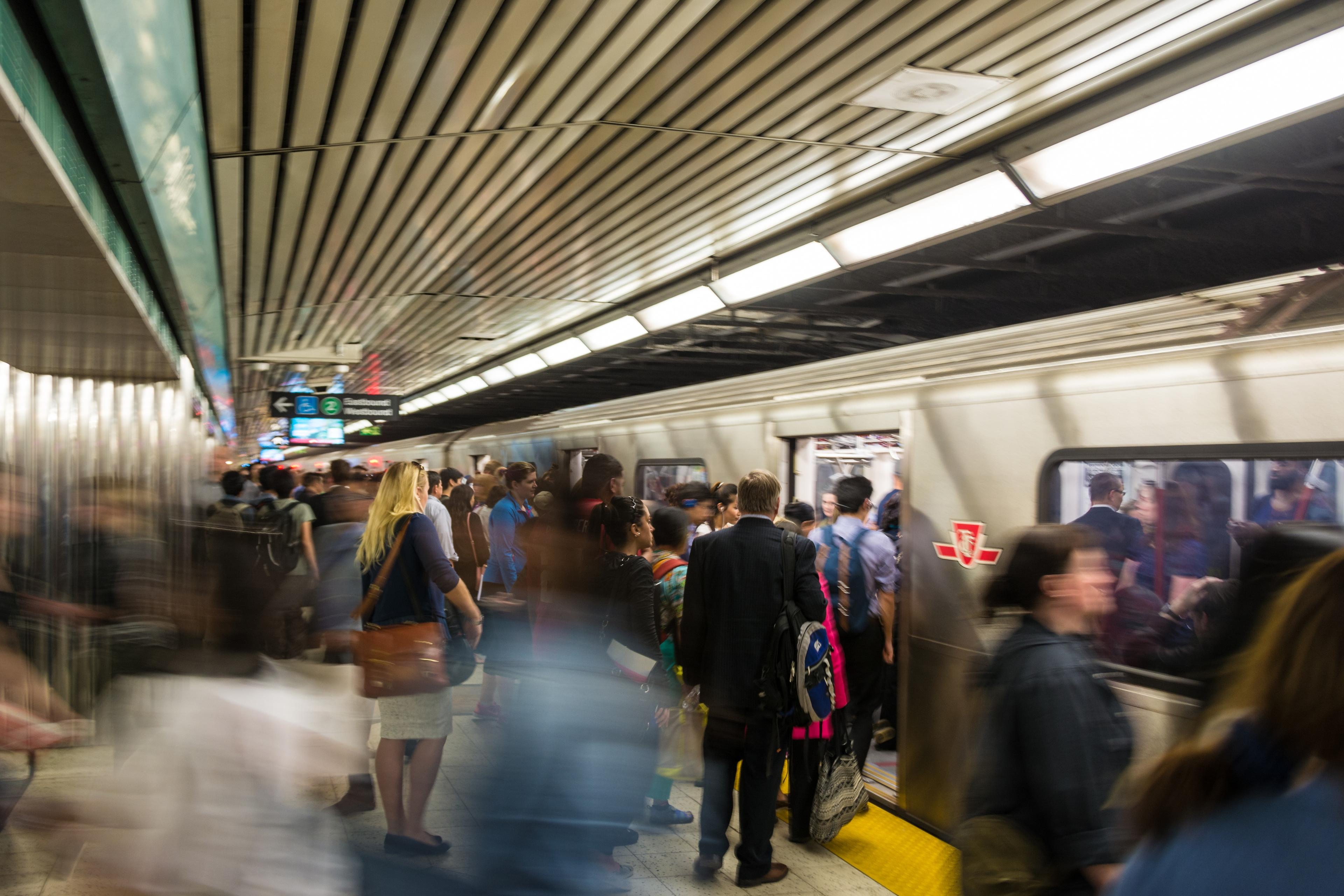 Photo of a busy underground train platform with people boarding and exiting a stationary train.